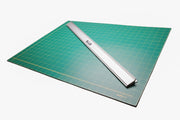 Green cutting mat with a metal ruler on a white background