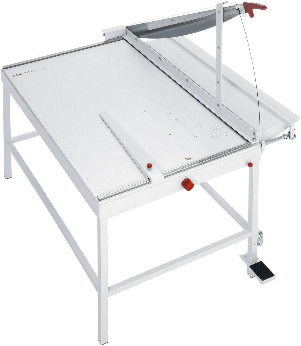 A white IDEAL 1110 A1 Manual Guillotine with a large cutting table and a stand, featuring a resharpenable blade and a foot pedal clamping mechanism.