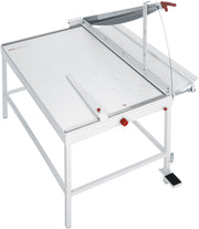 A white IDEAL 1110 A1 Manual Guillotine with a large cutting table and a stand, featuring a resharpenable blade and a foot pedal clamping mechanism.