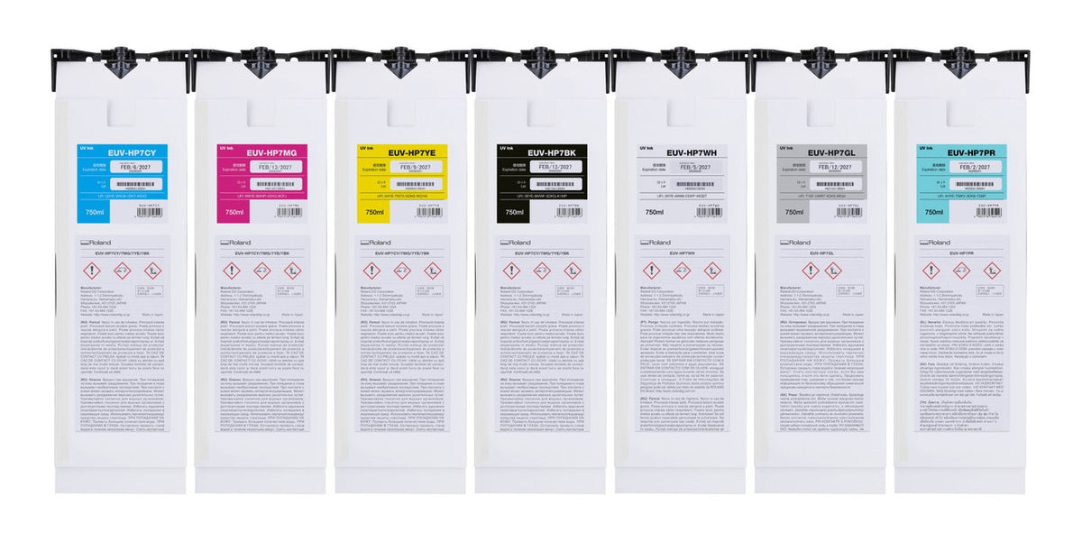 Seven white hanging pouches or sheets arranged side by side on a black rail, each with a different colored label card (cyan, magenta, yellow, black, white, gray, and light blue) and printed text and hazard symbols.