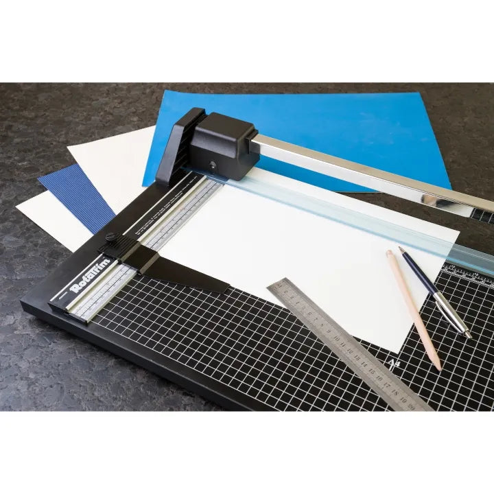 Paper cutter with cutting mat, ruler, and pencils on a dark surface. RotaTrim and Paper