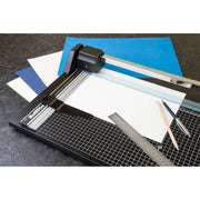 Paper cutter with cutting mat, ruler, and pencils on a dark surface. RotaTrim and Paper